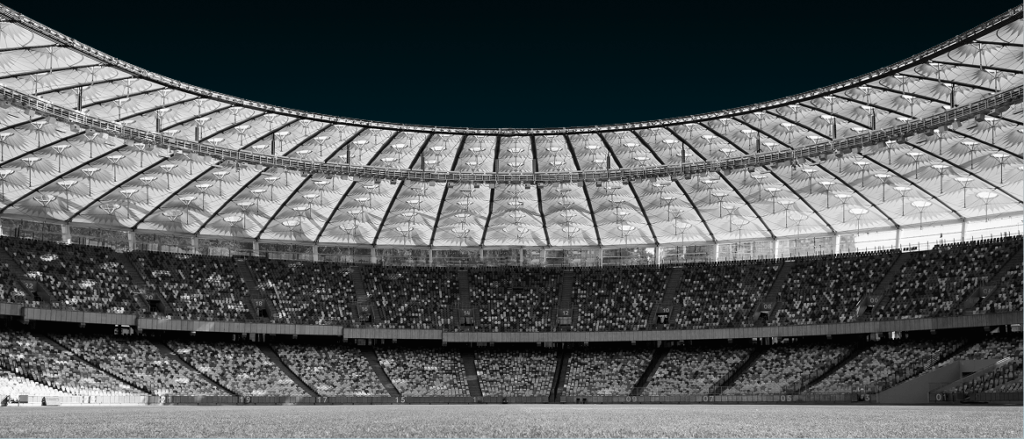 Stade de football rempli de spectateurs sous un toit incurvé, ambiance Coupe du Monde, illustration de l'article G-OPS sur le prono d'équipe