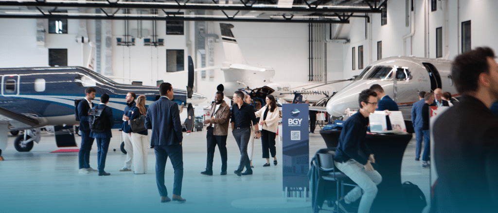 Business aviation professionals networking among private jets in the exhibition hangar at the Swiss Private Jets Show, Station Payerne (LSMP)