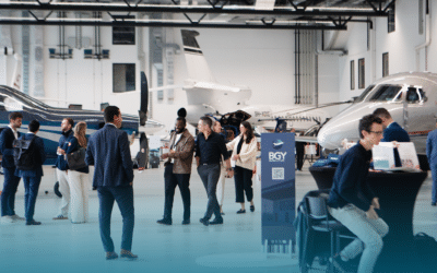 Business aviation professionals networking among private jets in the exhibition hangar at the Swiss Private Jets Show, Station Payerne (LSMP)